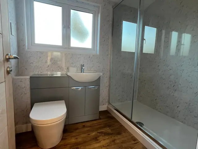 Finished shower room with a large walk-in shower, a grey vanity unit and toilet, and a wood-effect floor
